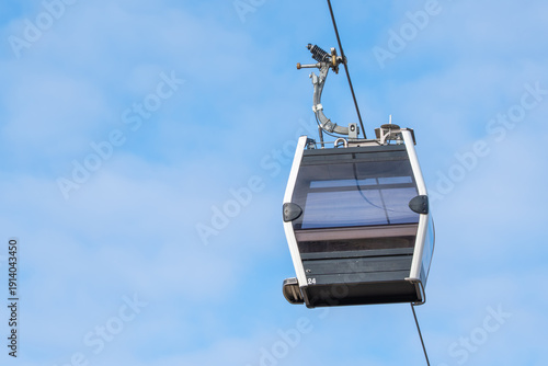 Bild auf Leinwand A cable car is suspended in the air, traveling along a track
