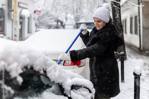 Woman clearing snow from car windshield on winter day