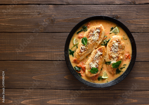 Chicken breast in creamy sauce with tomatoes and spinach on plate