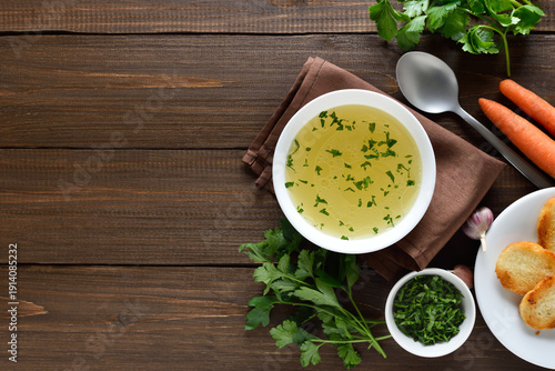 Chicken broth in bowl on wooden background