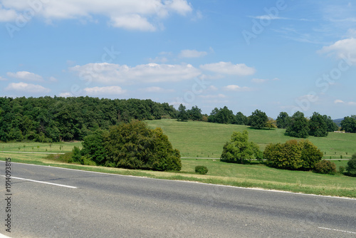 A beautiful landscape featuring a road leading to a green field under a blue sky.