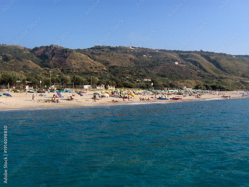 Obraz premium Beautiful panoramic view of the Calabrian coast during the summer season, featuring turquoise crystal-clear waters, dramatic rocky cliffs, and charming seaside scenery under bright blue skies. The