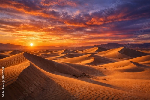 View of a vast desert at sunset with rolling sand dunes of varying sizes scattered across the scene and dramatic colorful evening sky.