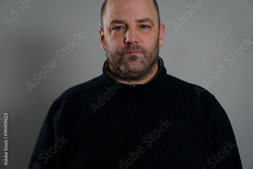 фотографія Middle-aged white man with a full beard and short hair wearing a black high collar knit wear, with an expressionless face