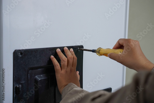 Cuadro en lienzo Close-up hand opening motor cover of clothes washing machine using screwdriver,