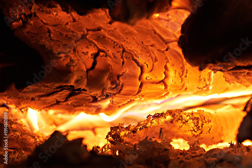 Image shows burning coals and ashes in a stove or fireplace. Selective focus