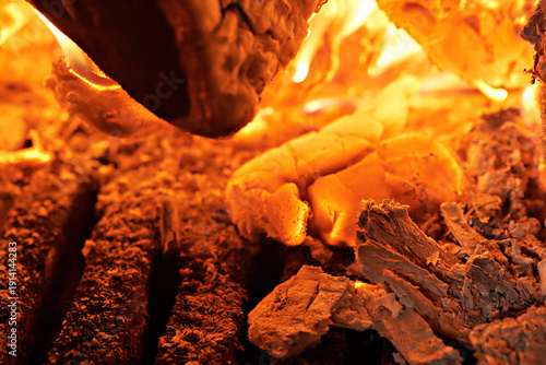 Image shows burning coals and ashes in a stove or fireplace. Selective focus