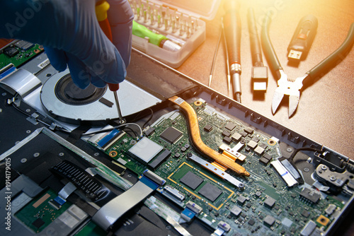 Side view of a technician repairing a laptop.