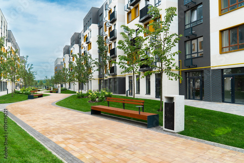 Fotografía Paved pedestrian path with wooden benches in a modern residential complex courty