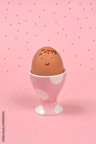 Vászonkép A brown chicken egg with a simple hand drawn smiling face sits in a pink polka d