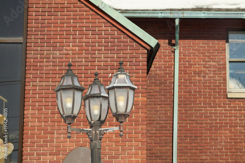 Bilde på lerret Traditional streetlamp in front of brick building with copper gutters