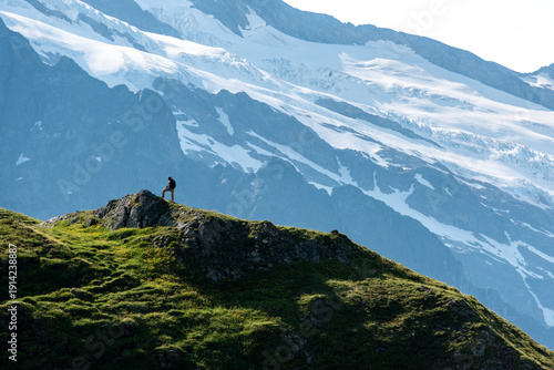 A hiker reached a small mountain summit and viewing towards a muh higer summit