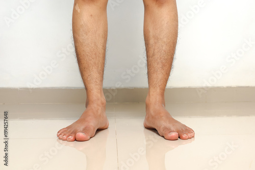 Cuadro en lienzo Bare human legs and feet standing on a reflective floor against a white wall