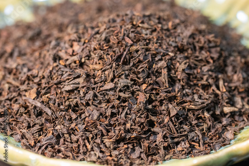 the coarse texture of a mound of dried, dark brown loose-leaf tea piled on a surface.