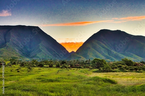 Sunrise with lush green field  over the west maui mountains. 