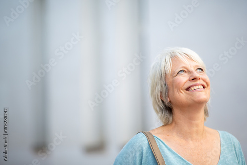 Quadro su tela Optimistic older woman looking up with joy in urban setting