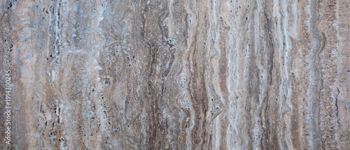 Wall with a textured surface that has grey and brown color. wall has rough texture and is made of stone