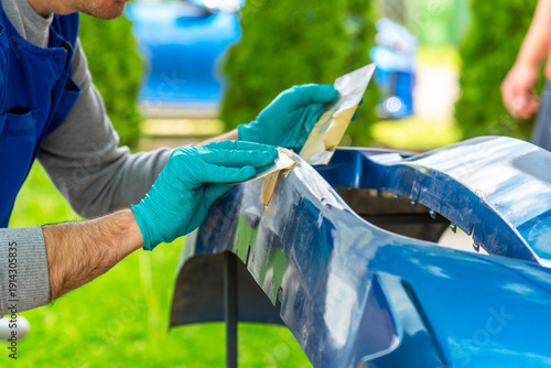 Repairing car body by puttying close up work after the accident by working sanding primer before painting.