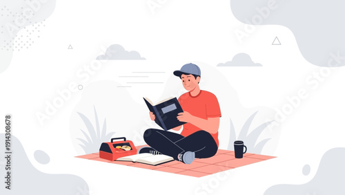 Young man reading a book on a picnic blanket outdoors