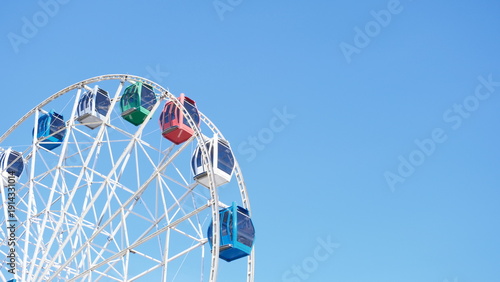 Foto Ferris wheel cabins against blue sky in city amusement park, backdrop with copy space