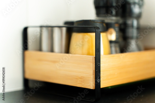 A close-up of kitchen spice rack with beautiful depth of field focused on the object. Assorted spice jars neatly arranged on a wooden stand, showcasing culinary ingredients.