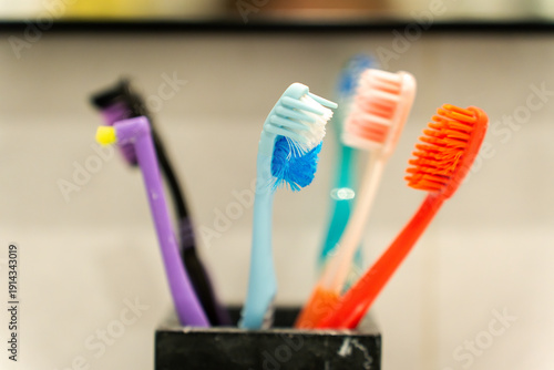 A close-up of many toothbrushes in a glass in the bathroom for the whole family. Colorful toothbrushes organized together, representing daily hygiene routine and family healthcare.