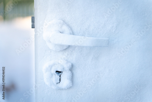 Frozen door handle and lock covered in frost during severe winter conditions. Close-up view of ice-covered door  house freezing from inside cold weather home insulation problems and climate challenges