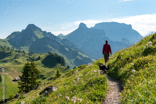 A woman hiking with her dog on a trail on the Schynige Platte in the Swiss alps