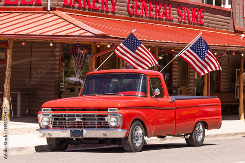 Fotografi Vintage Red Truck Parked Outside a General Store in Torrey, Utah, With American