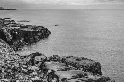A rocky shoreline with a calm ocean in the background