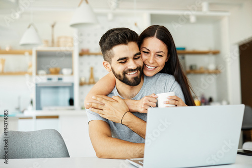 Wallpaper Mural Portrait of a young happy smiling couple using laptop together at home. Wireless technology computer concept Torontodigital.ca