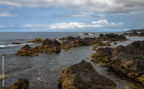Natural volcanic swimming pools at Biscoitos on Terceira Island, Azores, Portugal, with ocean ladder, rugged lava rocks, Atlantic waves, and dramatic coastal scenery under a blue sky