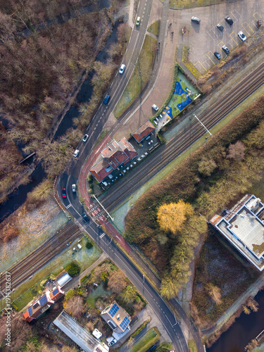 Portrait-orientation drone photograph of Het Tussenstation in Lisse, Netherlands, former train station landmark captured from above with nearby houses, roads and urban layout visible