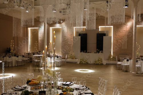 Foto Elegant wedding banquet hall with decorated tables, floral arrangements, candles and crystal chandeliers