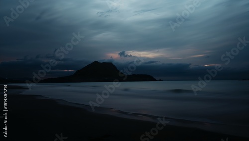 Cloudy Evening Sky Over a Mountain by the Sea With Gentle Waves at Dusk