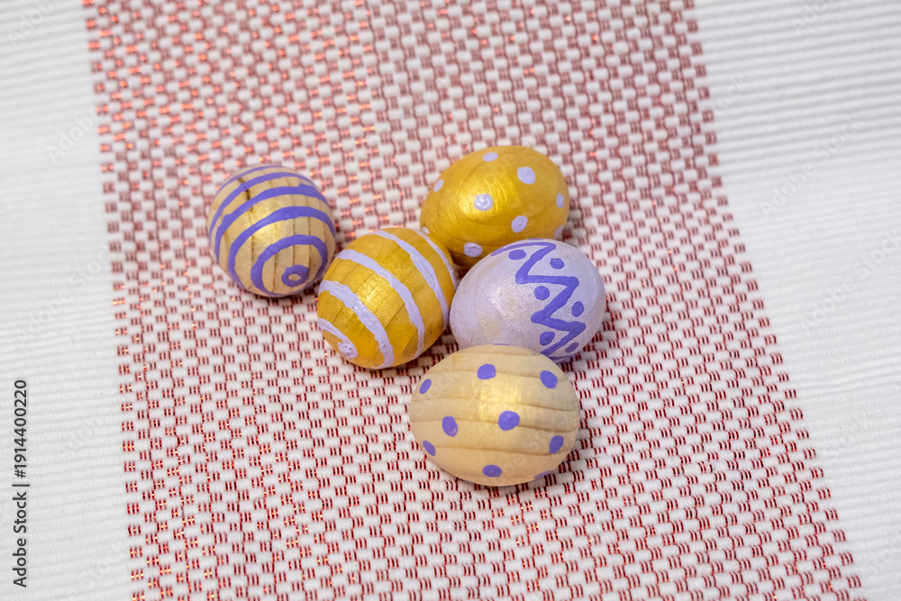 Fototapeta premium Hand-Painted Easter Eggs In Yellow And Purple Decorative Spring Crafts On Woven Cloth