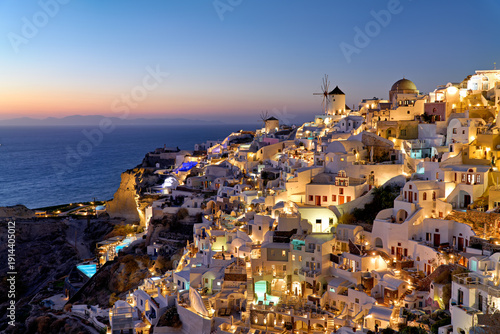Bild auf Leinwand Santorini's Oia village, illuminated at dusk, overlooking the sea