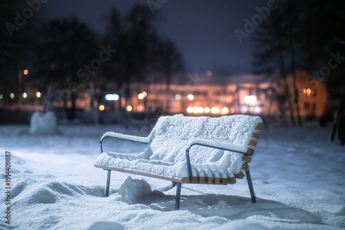 Zasnieżona ławka, zimowa noc, opady śniegu