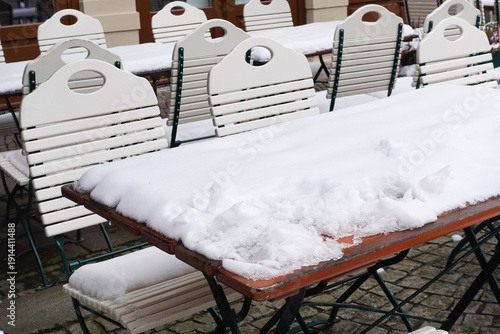 Snow covered outdoor restaurant tables and chairs in winter