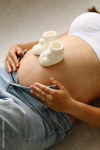 Pregnant woman holding belly with knitted baby booties, expecting baby concept