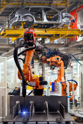 Fotografie Car assembly line. Industrial robot is welding metal part
