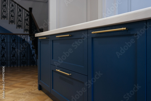 Modern luxury kitchen interior with beige cabinets and navy blue island.