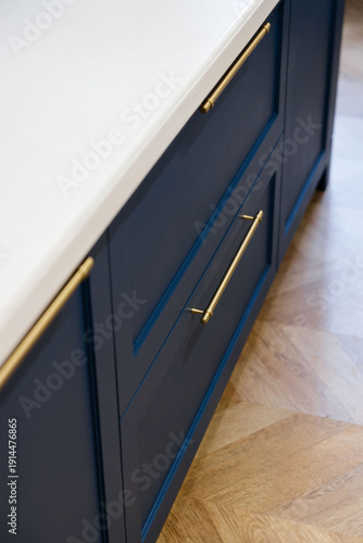 Modern luxury kitchen interior with beige cabinets and navy blue island.