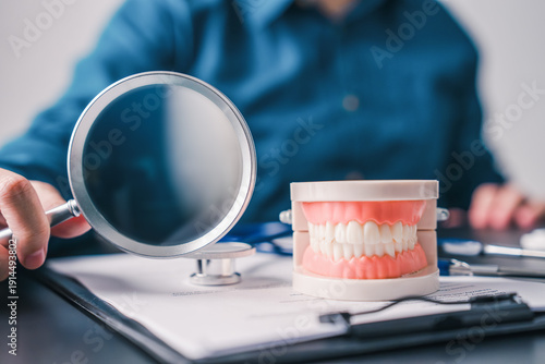 Professional dental checkup concept with tooth model and magnifying glass on clinic desk representing preventive care precision diagnosis and healthcare planning