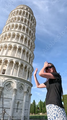 A tourist poses against the backdrop of the Leaning Tower of Pisa.