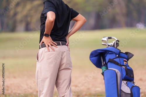 Rear view of golf player holding his lower back cause physical injure