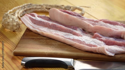 Close up fresh raw pork belly slices on wooden cutting board, uncooked meat texture and fat layers for cooking preparation, ingredient for frying, roasting, or homemade meals