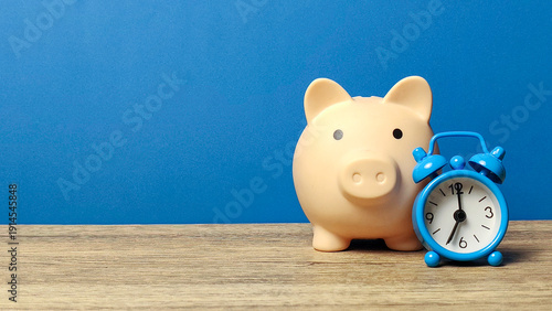 Pink Piggy Bank Next to Blue Alarm Clock Highlighting The Concept of Time is Money and Compound Interest Growth