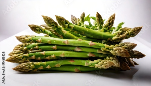 Fresh green asparagus spears stacked on a white surface, ready to cook.