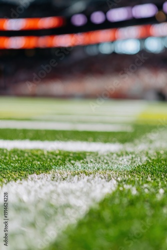 American football field turf with white yard lines and blurred stadium lights backdrop, professional sports arena background for advertising and marketing copy space